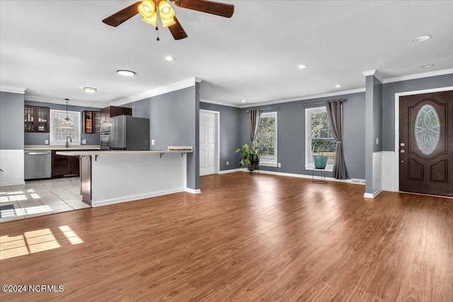 unfurnished living room with ceiling fan, light wood-type flooring, and ornamental molding