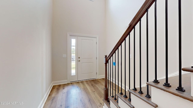 entrance foyer with light hardwood / wood-style flooring and a towering ceiling