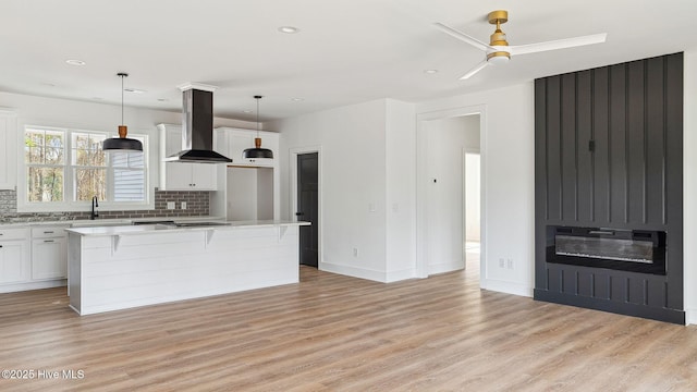 kitchen featuring white cabinets, hanging light fixtures, extractor fan, and a kitchen island