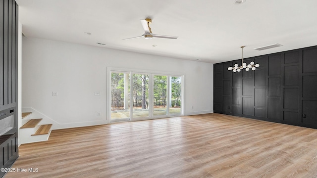 unfurnished living room featuring ceiling fan with notable chandelier and light hardwood / wood-style floors