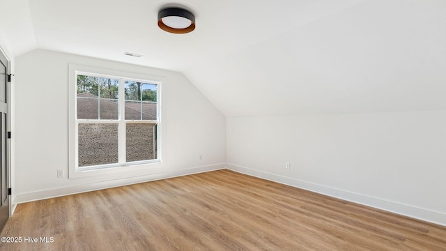 additional living space featuring light hardwood / wood-style floors and lofted ceiling