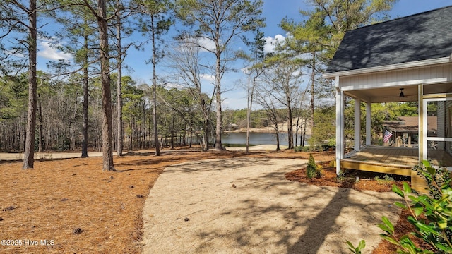 view of yard featuring ceiling fan and a deck with water view