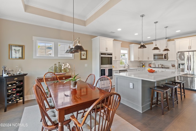 dining space featuring dark hardwood / wood-style flooring, sink, crown molding, and a tray ceiling