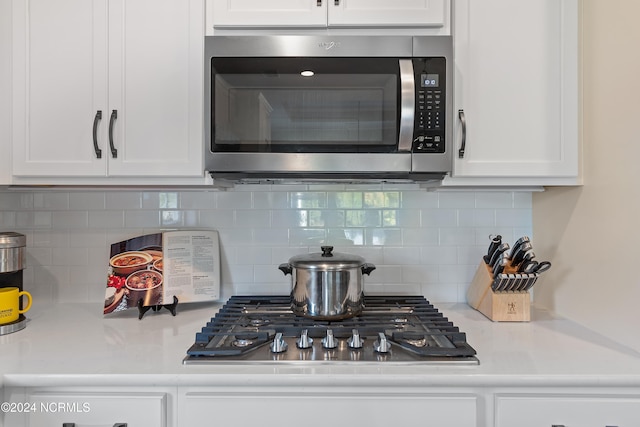 kitchen with white cabinets, appliances with stainless steel finishes, and tasteful backsplash