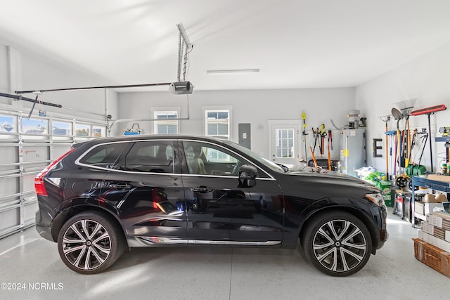 garage featuring water heater, a garage door opener, and electric panel