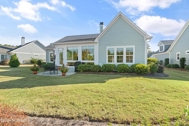 rear view of house featuring a lawn and a patio