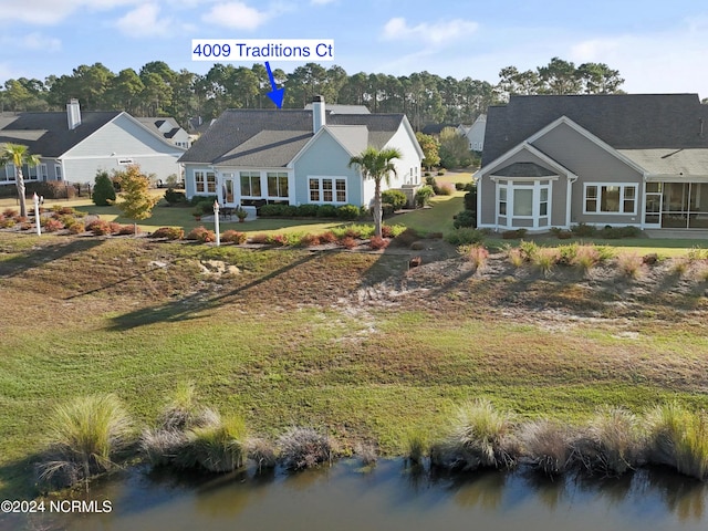 back of house with a water view and a lawn