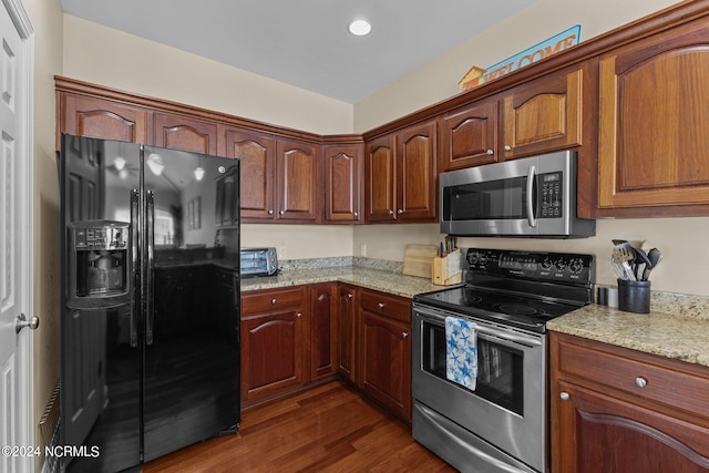 kitchen with dark hardwood / wood-style floors, light stone countertops, and stainless steel appliances