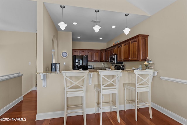 kitchen featuring black refrigerator with ice dispenser, kitchen peninsula, dark hardwood / wood-style floors, and a breakfast bar area