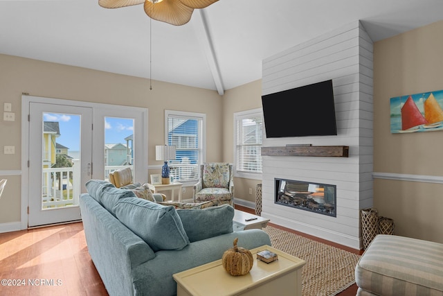 living room featuring lofted ceiling, wood-type flooring, a fireplace, and ceiling fan