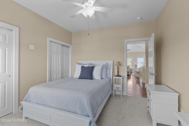 bedroom featuring light colored carpet, a closet, and ceiling fan