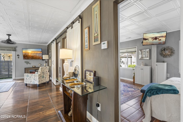 hallway with dark wood-type flooring, ornamental molding, and a barn door