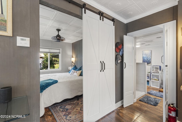 bedroom with dark wood-type flooring and a barn door