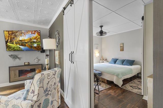 bedroom with dark wood-type flooring, a barn door, and crown molding