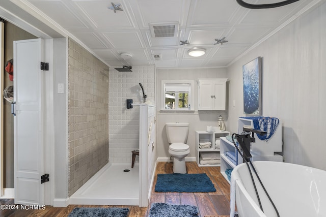 bathroom featuring a tile shower, hardwood / wood-style flooring, and toilet