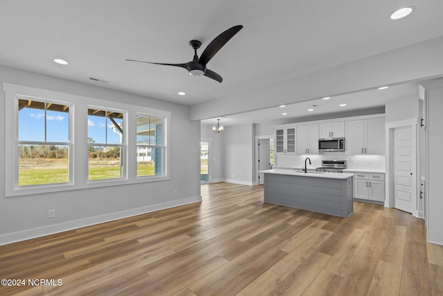 kitchen featuring a center island with sink, appliances with stainless steel finishes, white cabinetry, light hardwood / wood-style flooring, and sink