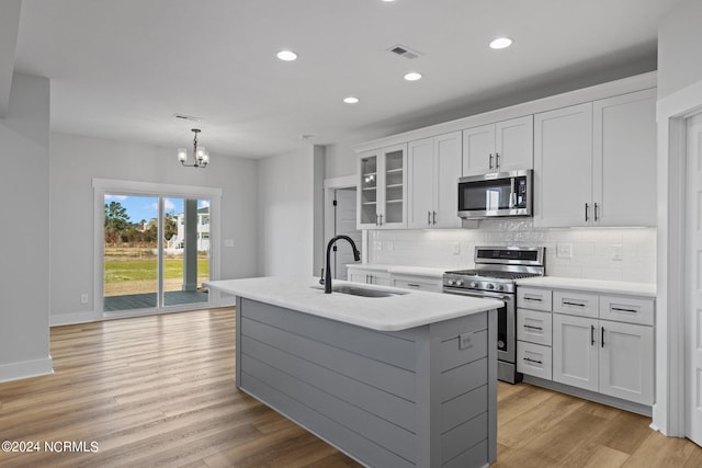 kitchen with a center island with sink, sink, light hardwood / wood-style flooring, and stainless steel appliances