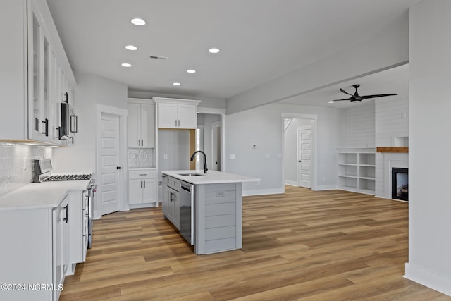 kitchen featuring tasteful backsplash, an island with sink, white cabinetry, sink, and stainless steel appliances