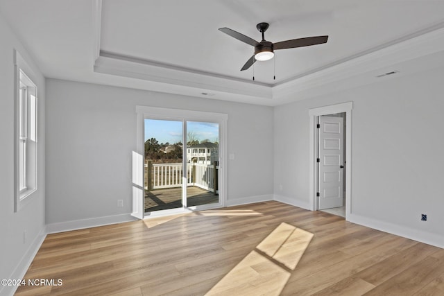 spare room with light hardwood / wood-style flooring, a tray ceiling, and ceiling fan