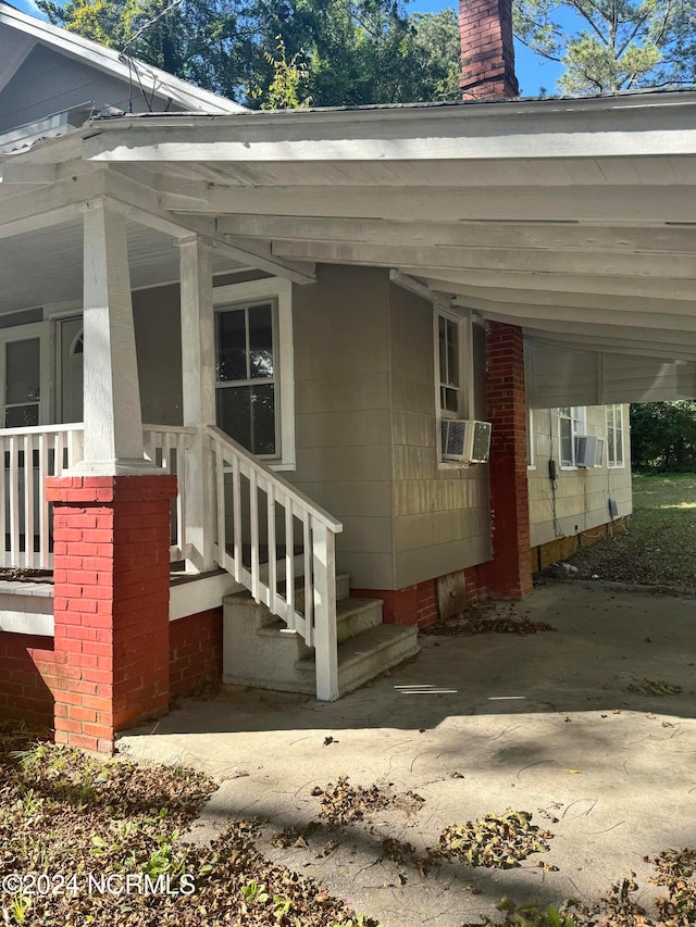 entrance to property with cooling unit, covered porch, and a carport