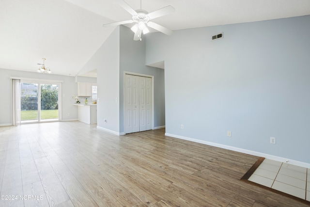 interior space featuring high vaulted ceiling, ceiling fan with notable chandelier, and light hardwood / wood-style floors