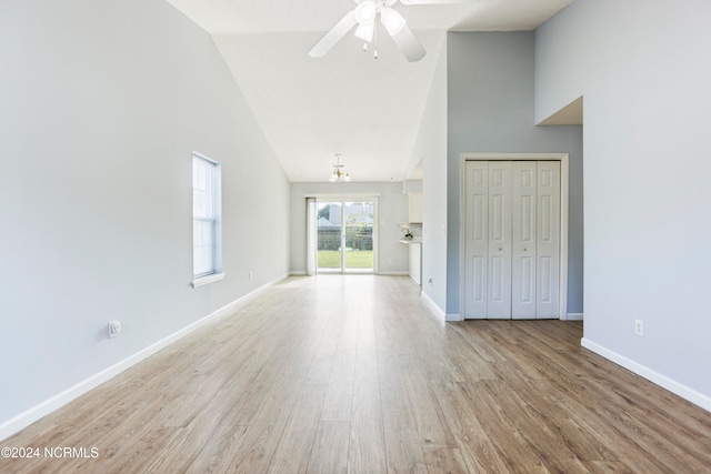 interior space featuring light hardwood / wood-style flooring, ceiling fan with notable chandelier, and high vaulted ceiling