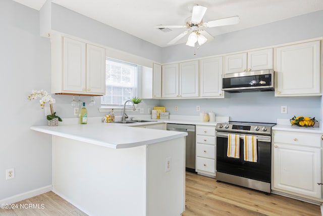 kitchen with appliances with stainless steel finishes, kitchen peninsula, white cabinets, and sink