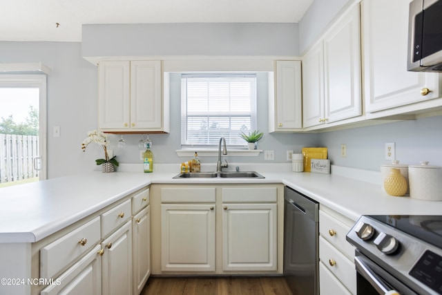 kitchen with kitchen peninsula, white cabinets, dark hardwood / wood-style flooring, appliances with stainless steel finishes, and sink