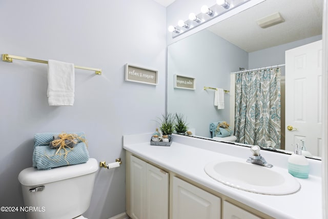 bathroom featuring vanity, a textured ceiling, and toilet