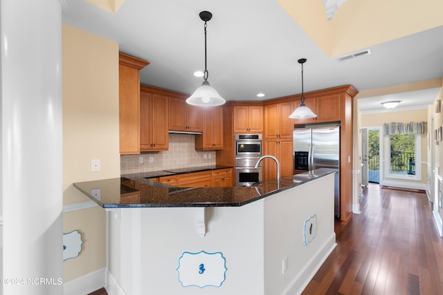 kitchen with kitchen peninsula, dark stone countertops, decorative light fixtures, and dark hardwood / wood-style flooring