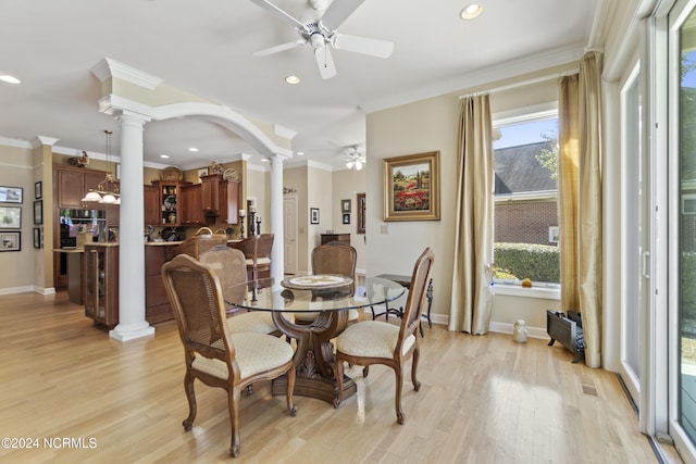 dining area featuring crown molding, decorative columns, light wood-type flooring, and ceiling fan