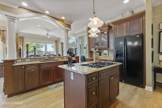 kitchen with stainless steel gas stovetop, decorative columns, kitchen peninsula, and black fridge with ice dispenser