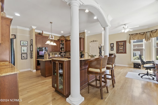 kitchen featuring decorative columns, light hardwood / wood-style floors, ceiling fan, decorative light fixtures, and crown molding