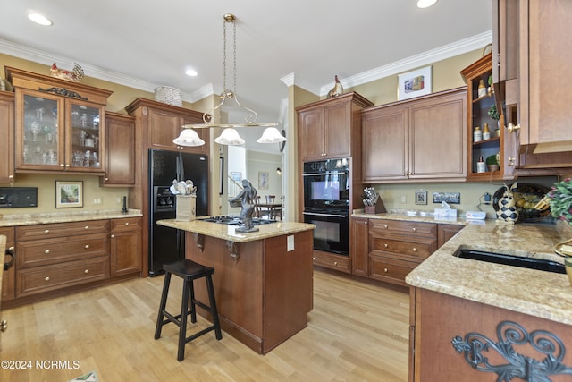 kitchen with light hardwood / wood-style floors, crown molding, black appliances, and hanging light fixtures