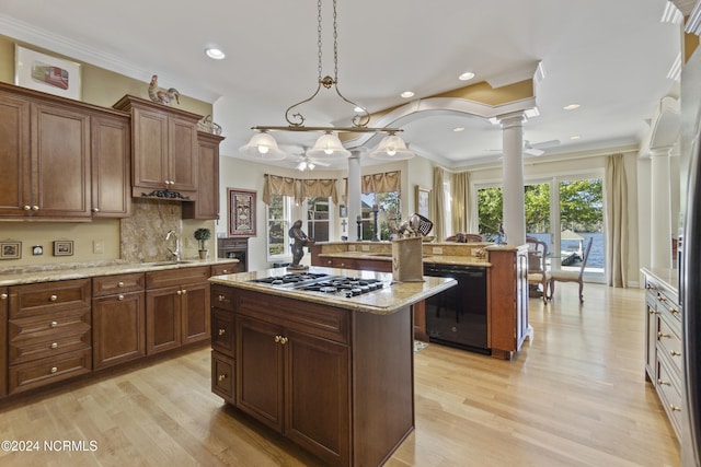 kitchen with decorative columns, a center island, pendant lighting, stainless steel gas stovetop, and light hardwood / wood-style flooring