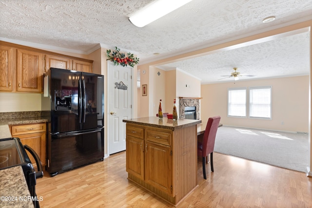 kitchen featuring black appliances, light wood-type flooring, a kitchen island, a textured ceiling, and ceiling fan