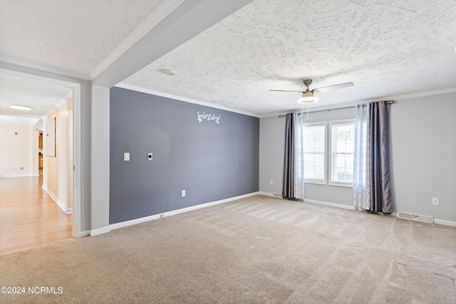 unfurnished room with a textured ceiling, crown molding, baseboards, light carpet, and a ceiling fan