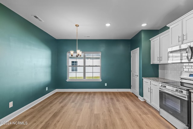 kitchen featuring tasteful backsplash, white cabinets, an inviting chandelier, light hardwood / wood-style flooring, and appliances with stainless steel finishes