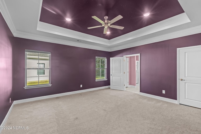 carpeted spare room with crown molding, a tray ceiling, and ceiling fan