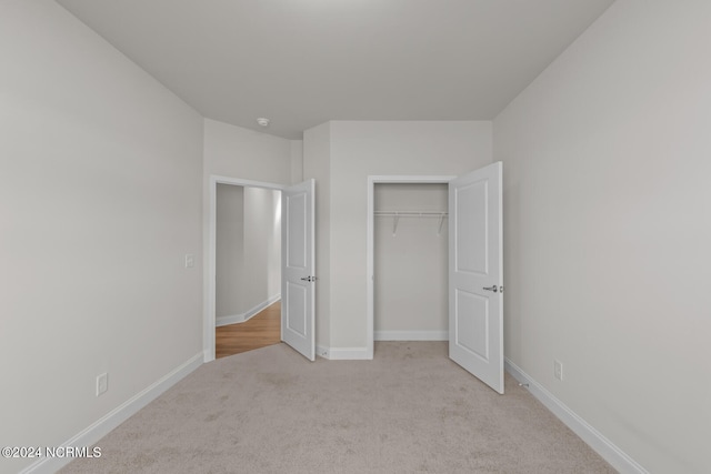 unfurnished bedroom with light carpet and a closet