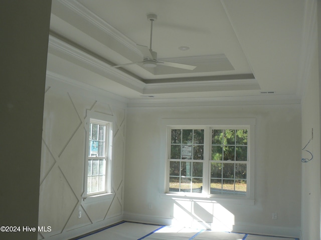 interior space with a raised ceiling, ceiling fan, and ornamental molding