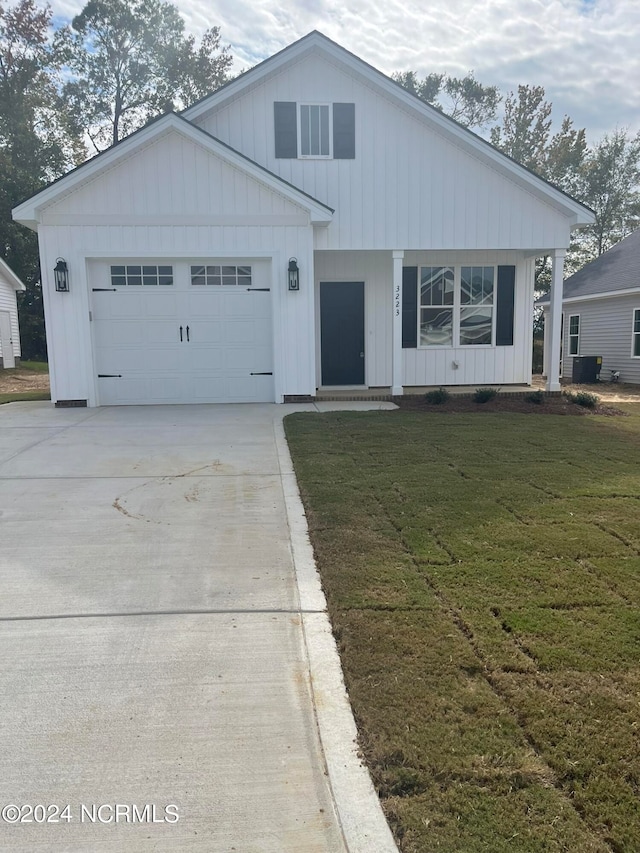 view of front of house featuring a front yard, a garage, and central AC unit