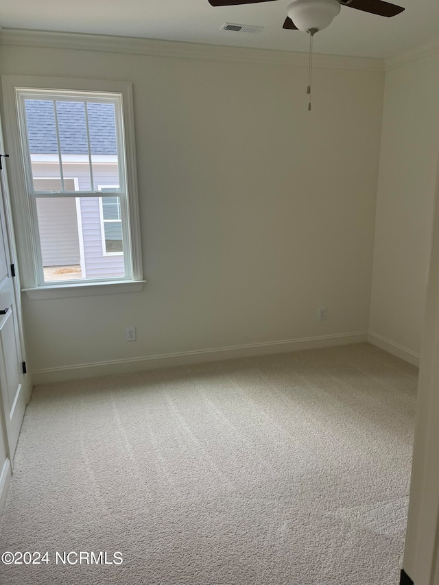 spare room featuring light carpet, crown molding, and ceiling fan