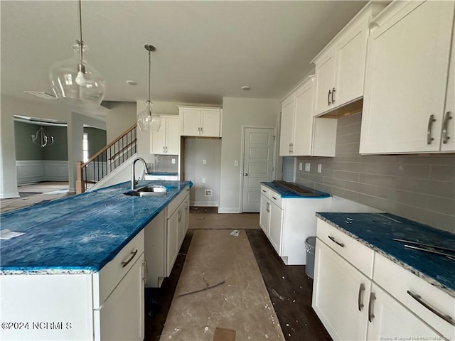 kitchen featuring dark hardwood / wood-style floors, a center island with sink, sink, pendant lighting, and white cabinets