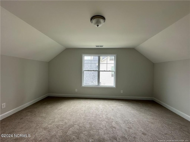 additional living space featuring carpet floors and vaulted ceiling