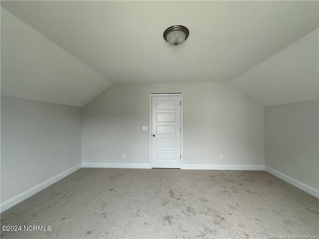 bonus room with vaulted ceiling and light carpet