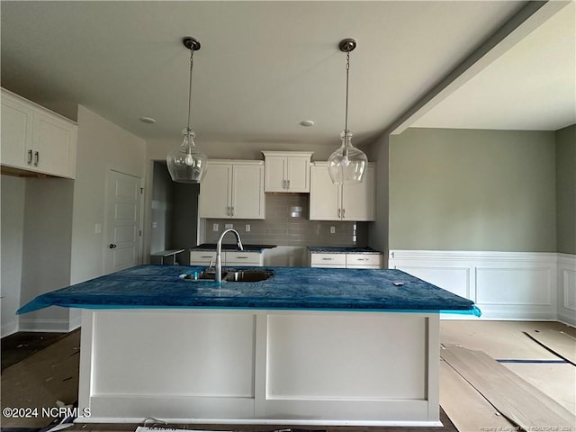 kitchen with backsplash, sink, an island with sink, and white cabinets