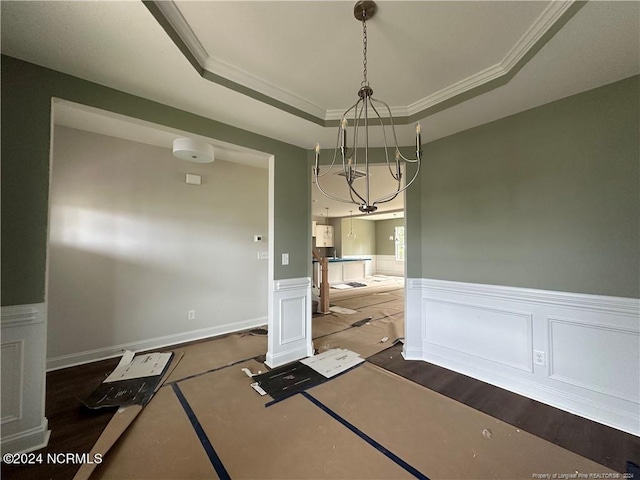 unfurnished dining area featuring dark wood-type flooring, a tray ceiling, ornamental molding, and an inviting chandelier