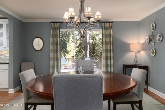 dining area with ornamental molding, light hardwood / wood-style flooring, and an inviting chandelier