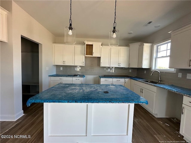 kitchen with a kitchen island, sink, pendant lighting, white cabinets, and dark hardwood / wood-style flooring